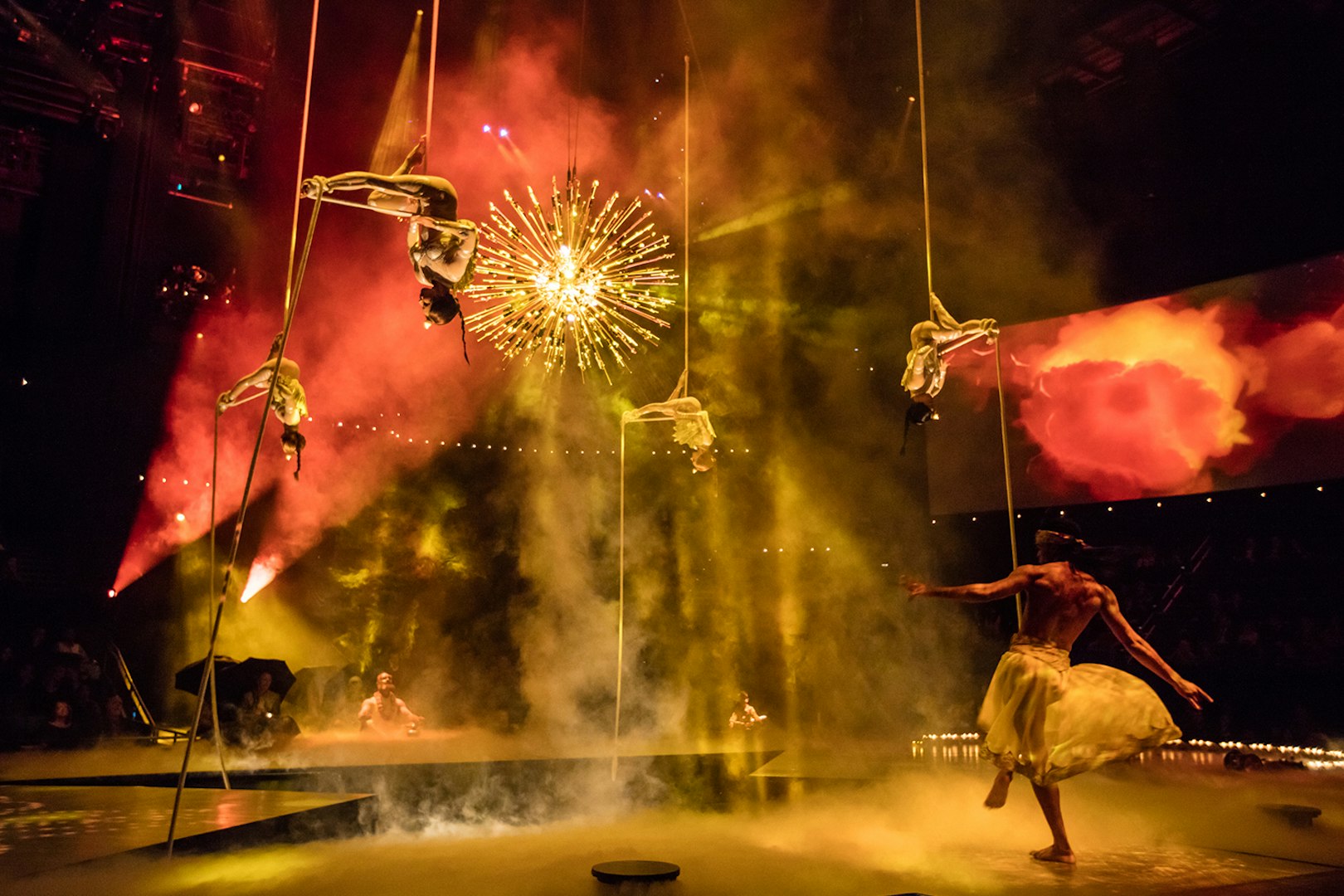 Aerial performers in The Beatles LOVE show with vibrant lighting and stage effects.