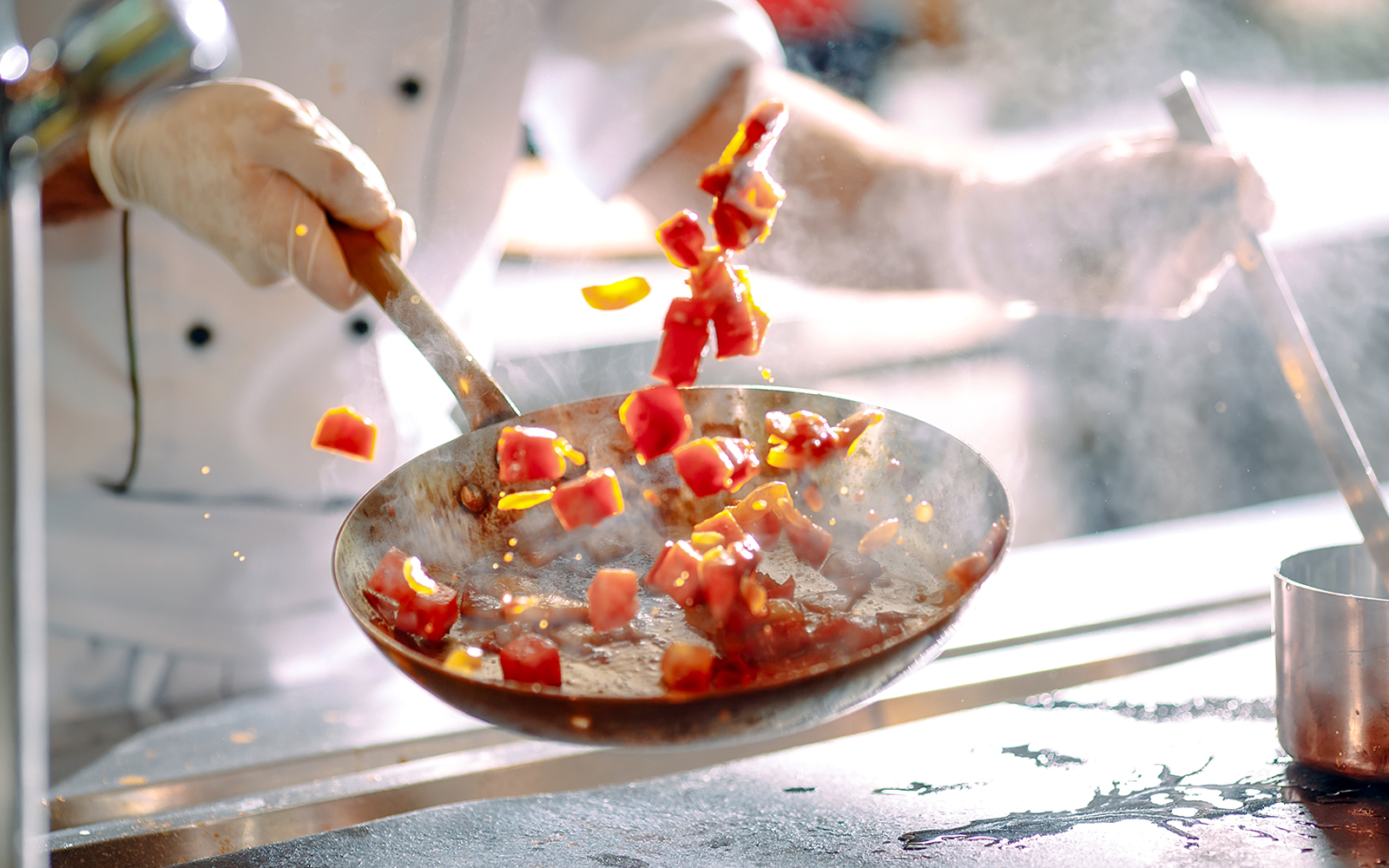 Chef stir frying colorful vegetables in a pan.