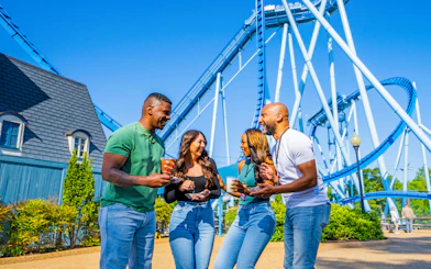 Group enjoying drinks near roller coaster at Busch Gardens Williamsburg.
