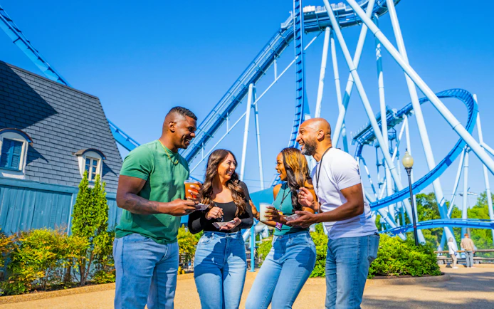Group enjoying drinks near roller coaster at Busch Gardens Williamsburg.