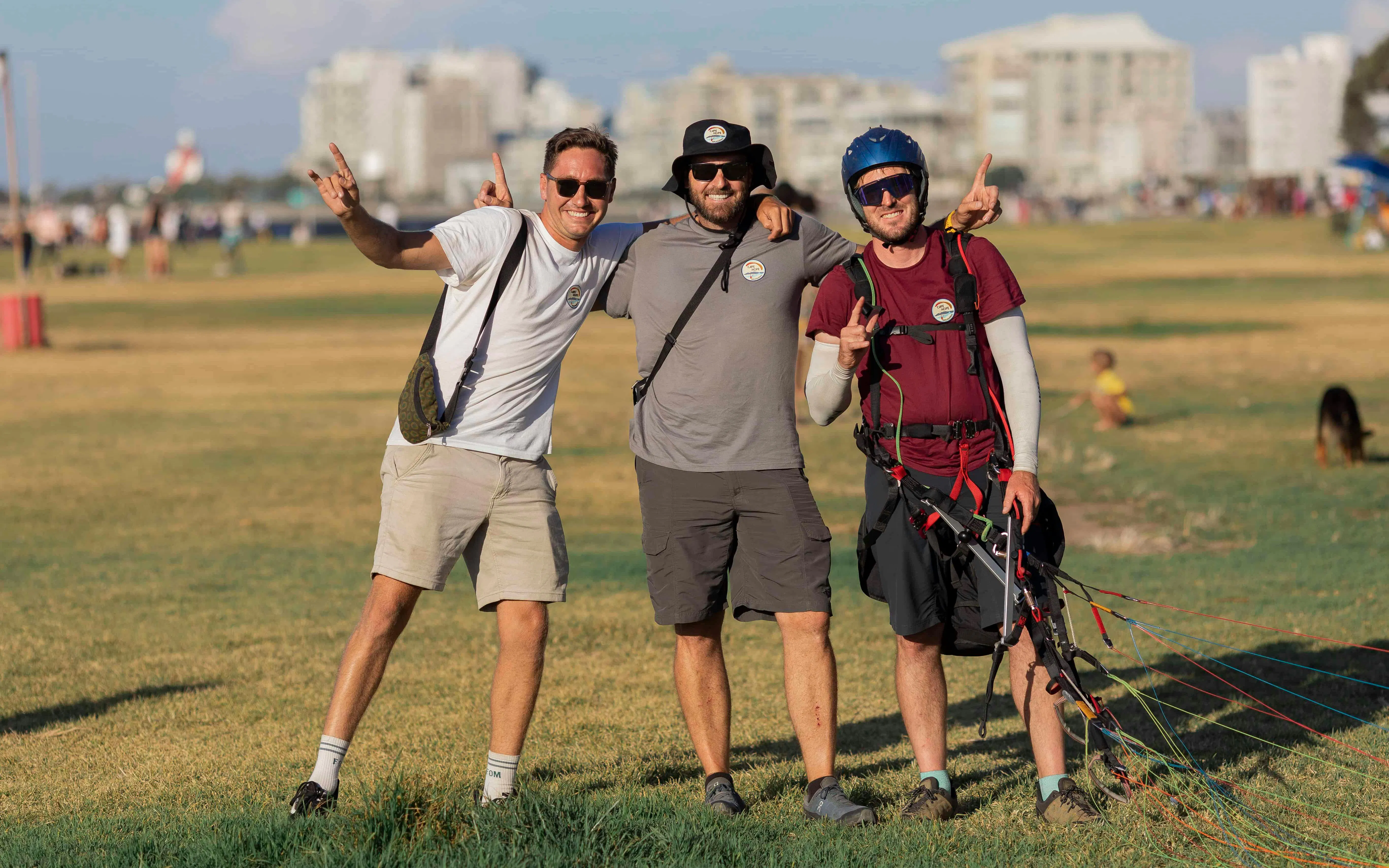 Guests preparing for tandem paragliding in Cape Town, standing on a grassy field.