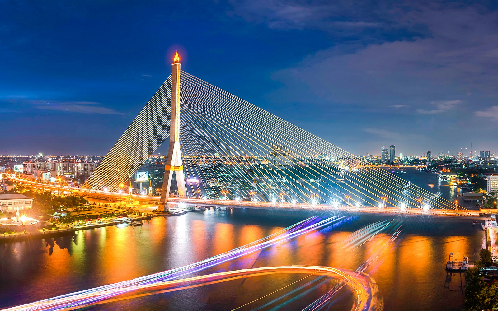 Aerial view of Rama VIII Bridge illuminated at night over the Chao Phraya River in Bangkok.