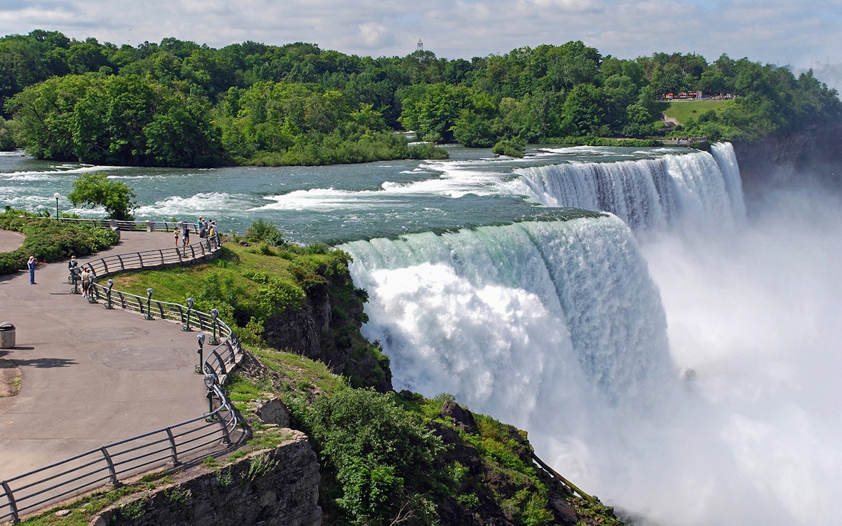 Visitors at Niagara Falls viewpoint overlooking the waterfall and river.