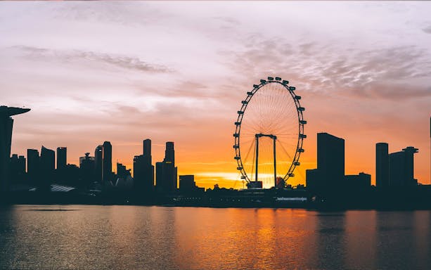 Singapore skyline with Ferris wheel at sunset during bay cruise.