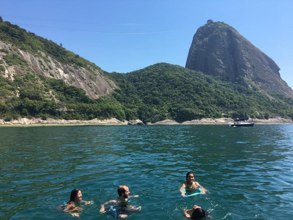 Tourists swimming near Sugarloaf Mountain during Rio de Janeiro cruise tour.