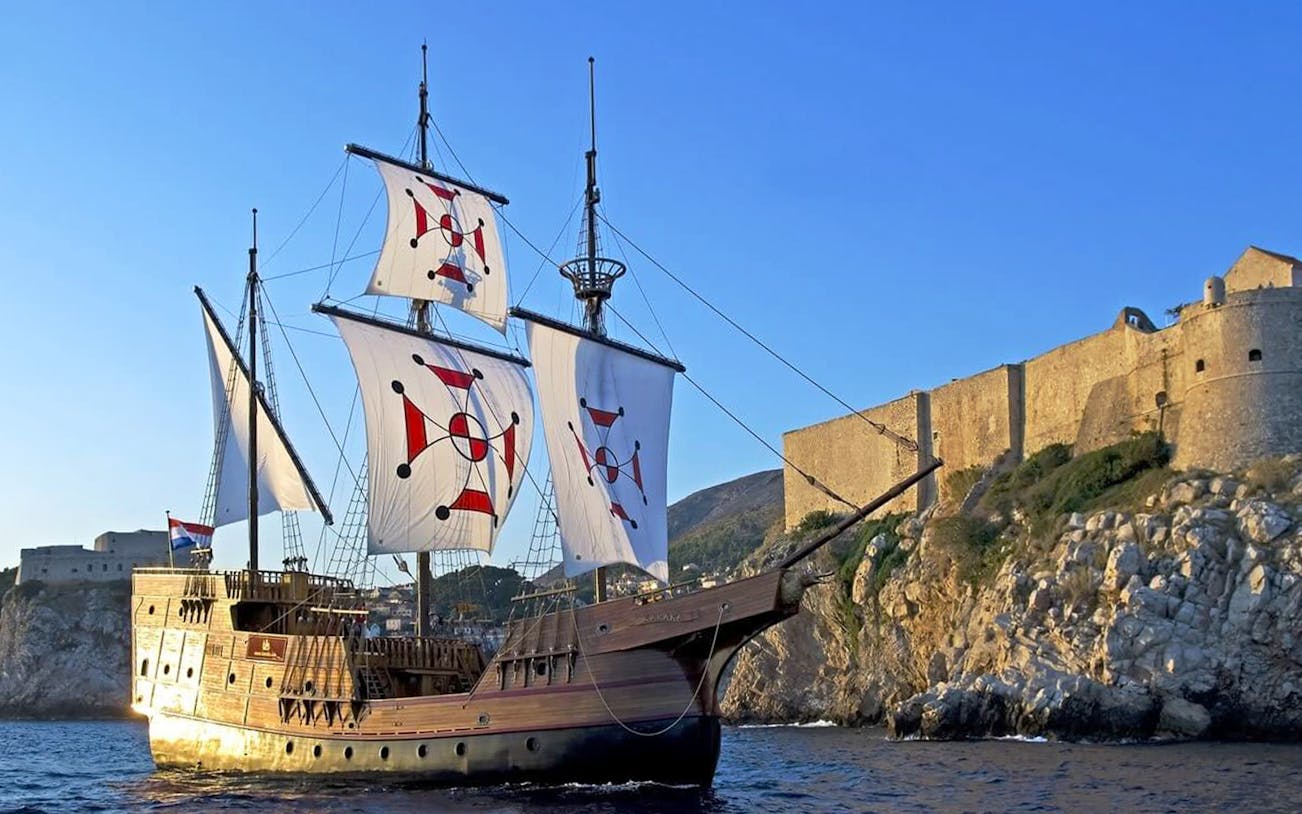 Historic ship sailing near Dubrovnik's ancient walls on Elaphite Islands cruise.