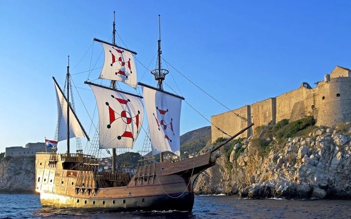 Historic ship sailing near Dubrovnik's ancient walls on Elaphite Islands cruise.