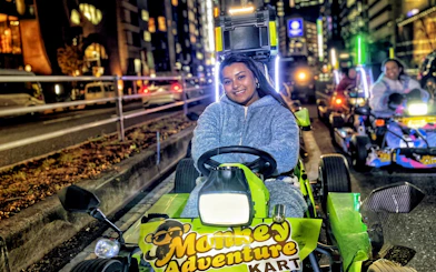 Person driving a go-kart on a Tokyo street at night during a Shibuya to Shinjuku tour.