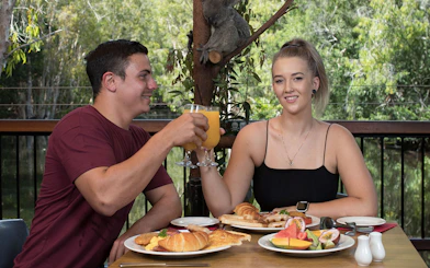 Breakfast with koalas at Hartley's Crocodile Adventures, featuring a couple toasting with orange juice.
