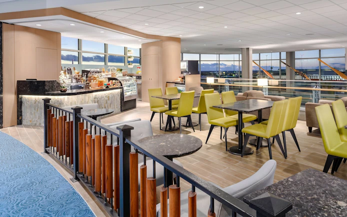 Plaza Premium Lounge seating area with tables and chairs at Vancouver International Airport.