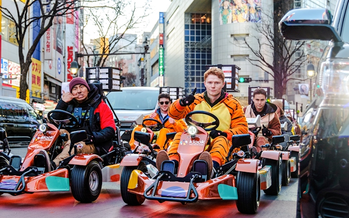 Tourists in costumes driving go-karts on Shibuya streets, Tokyo.
