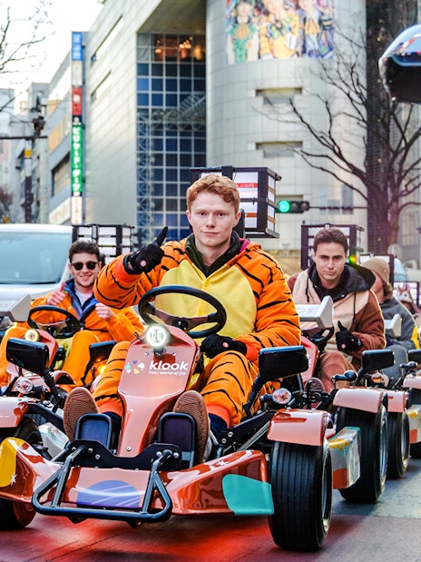 Tourists in costumes driving go-karts on Shibuya streets, Tokyo.