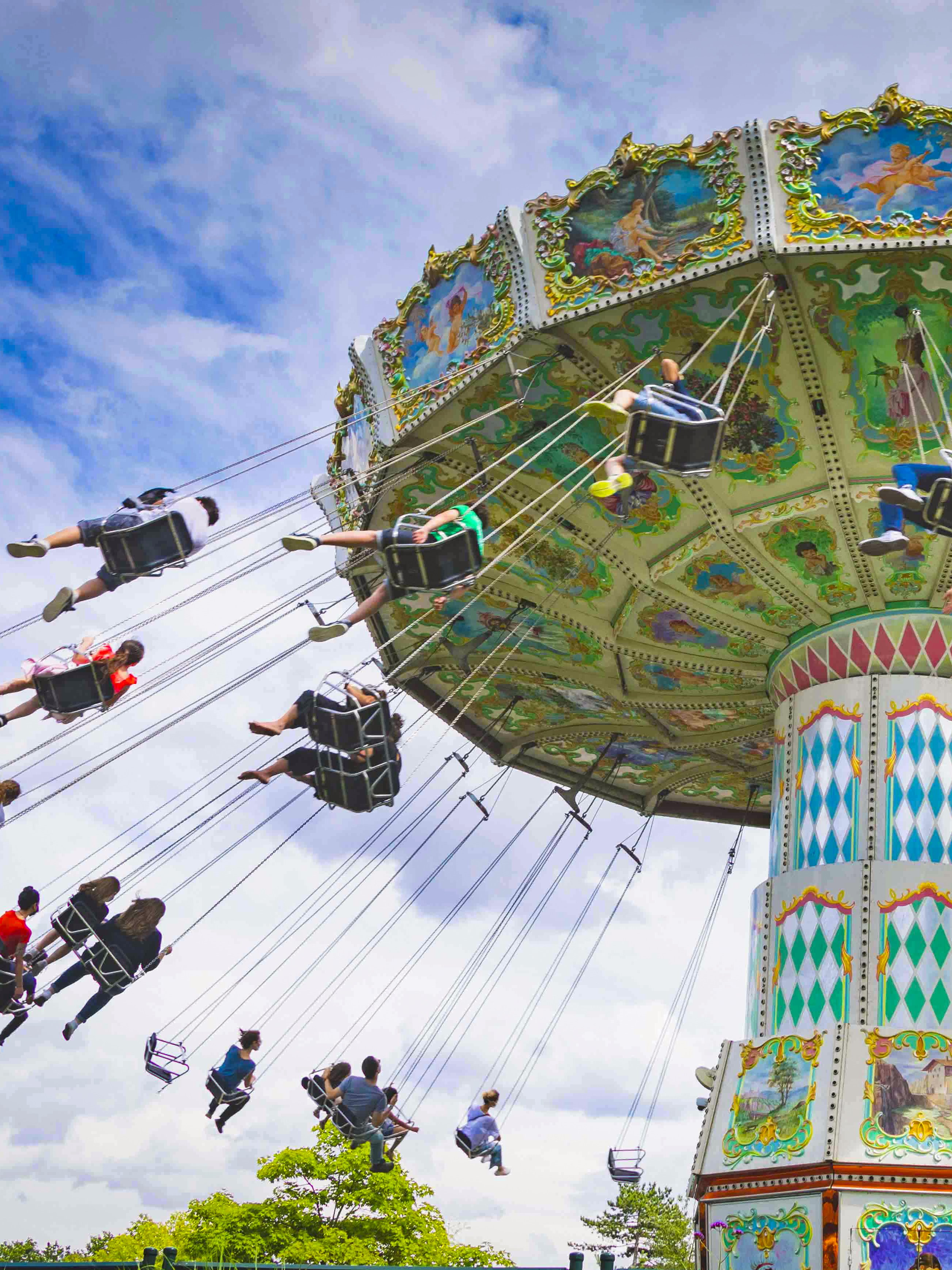 Carousel swing ride at Le Jardin d'Acclimatation, Paris, with people enjoying the attraction.