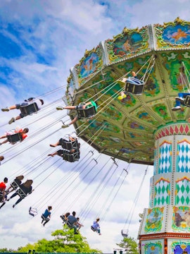 Carousel swing ride at Le Jardin d'Acclimatation, Paris, with people enjoying the attraction.