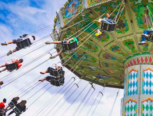Carousel swing ride at Le Jardin d'Acclimatation, Paris, with people enjoying the attraction.
