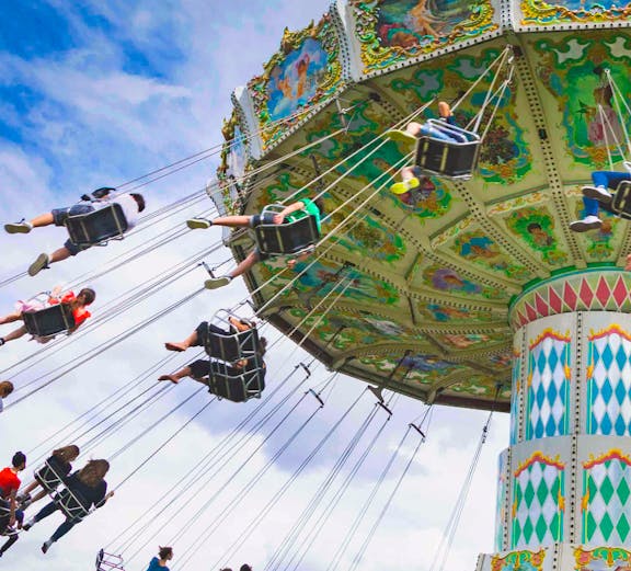 Carousel swing ride at Le Jardin d'Acclimatation, Paris, with people enjoying the attraction.