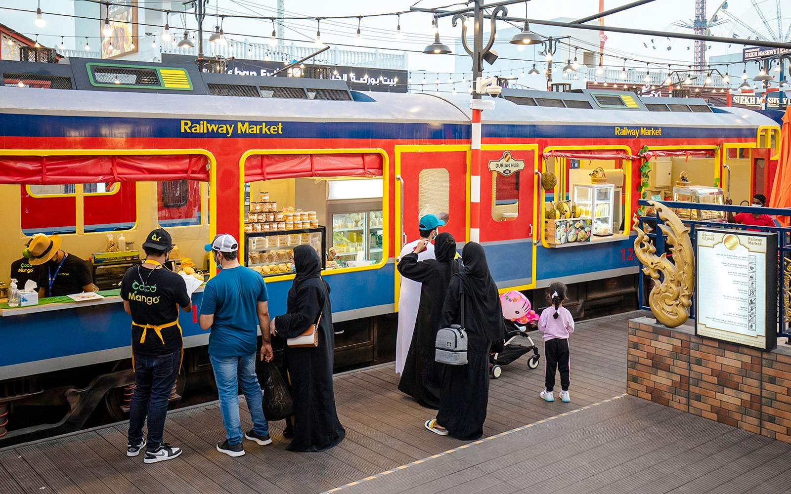 Visitors at a colorful train-themed stall in the Railway Market, Global Village.