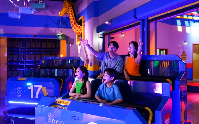 Family enjoying a ride at Legoland Korea with colorful lights and LEGO decorations.
