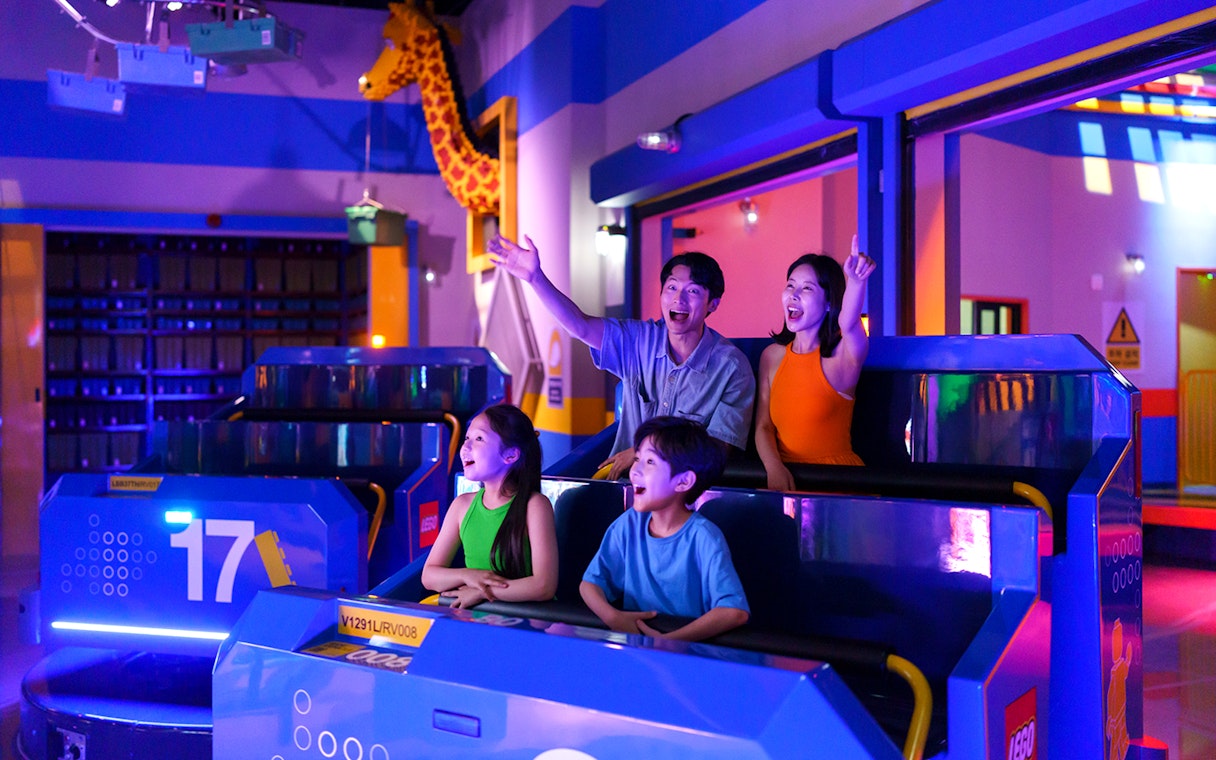 Family enjoying a ride at Legoland Korea with colorful lights and LEGO decorations.