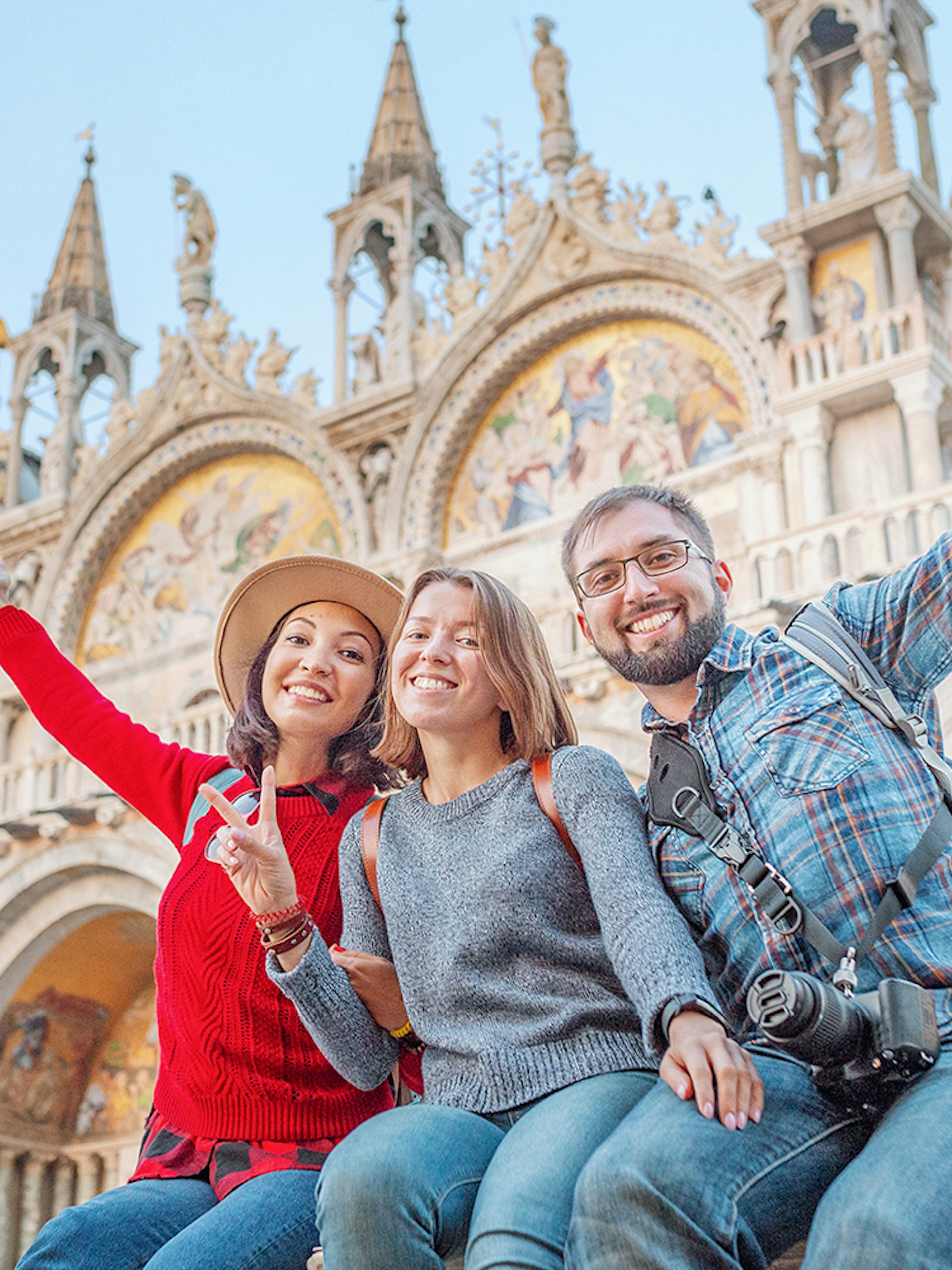 Friends enjoying San Marco Square, Venice, with St. Mark's Basilica in the background.