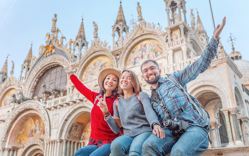Friends enjoying San Marco Square, Venice, with St. Mark's Basilica in the background.