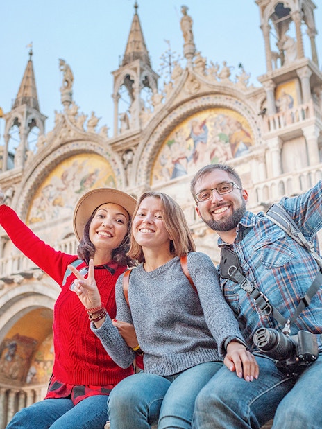 Friends enjoying San Marco Square, Venice, with St. Mark's Basilica in the background.