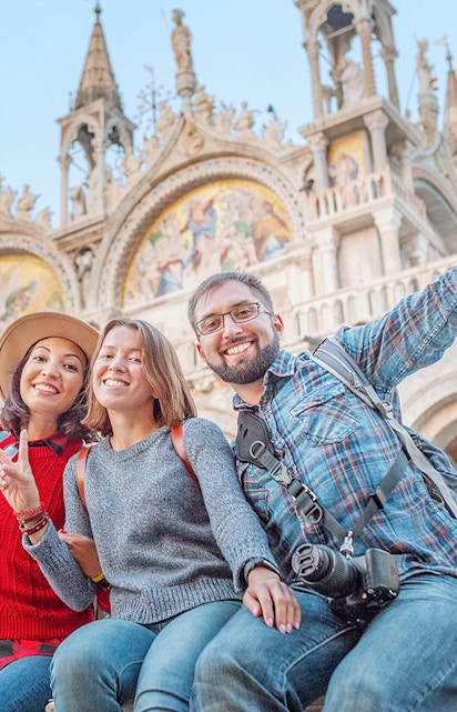 Friends enjoying San Marco Square, Venice, with St. Mark's Basilica in the background.