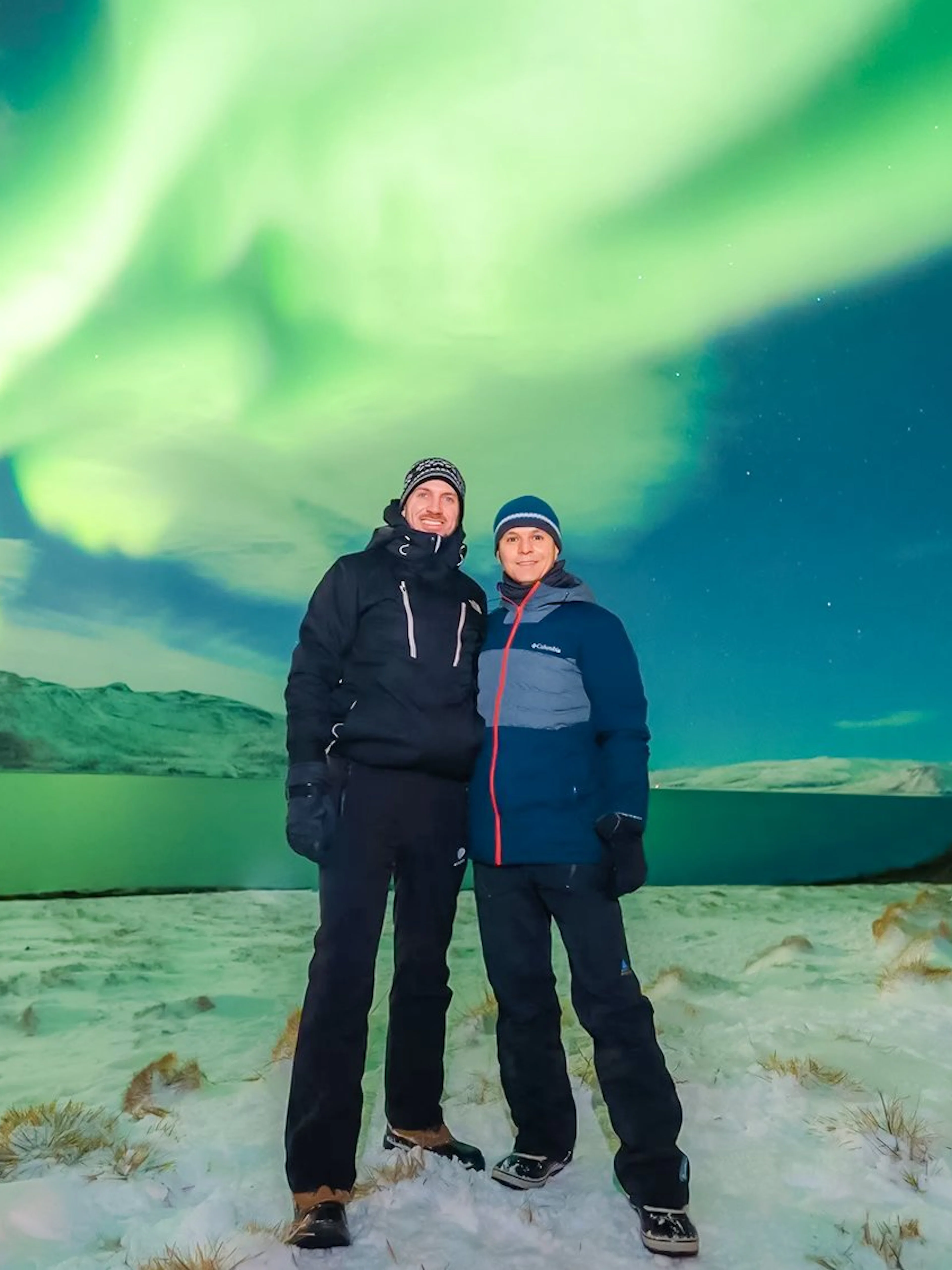 Couple standing under Northern Lights in Tromso, Norway.