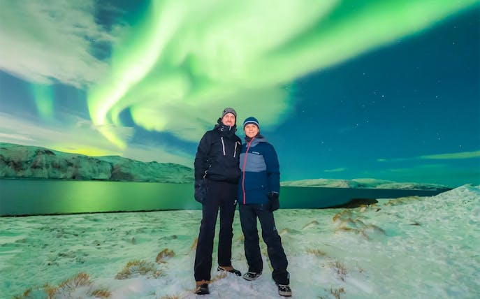 Couple standing under Northern Lights in Tromso, Norway.