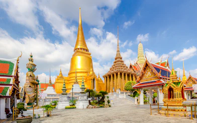 Wat Phra Kaew temple complex with golden stupa and guardian statue, Grand Palace, Bangkok.