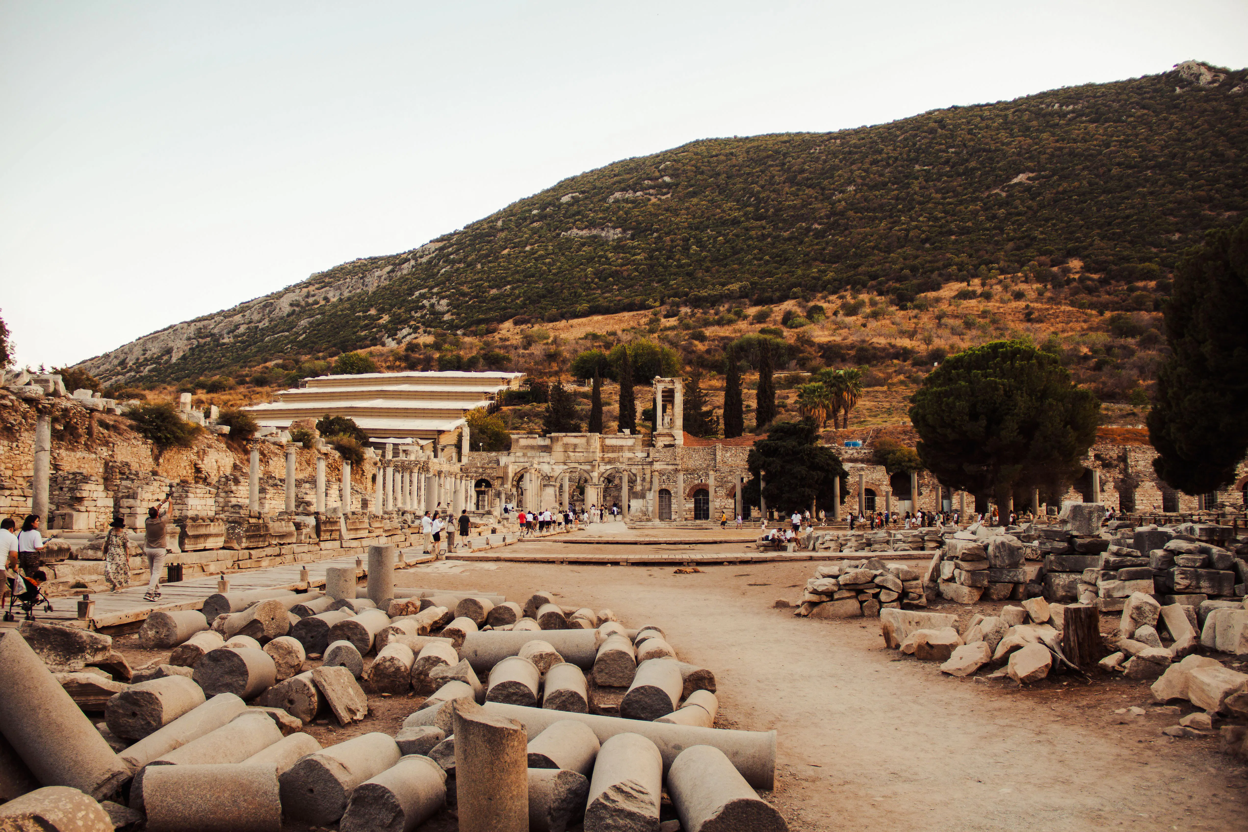 Ancient ruins of Ephesus with tourists exploring, Kusadasi backdrop.
