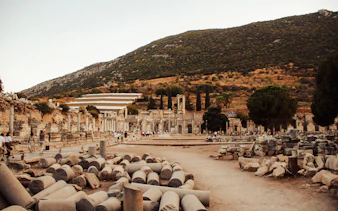 Ancient ruins of Ephesus with tourists exploring, Kusadasi backdrop.