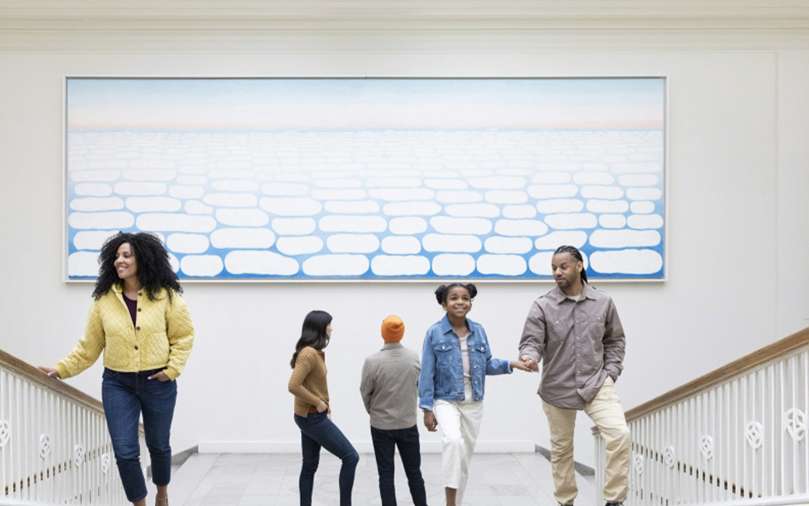 Visitors ascending stairs at The Art Institute of Chicago under a large abstract painting.