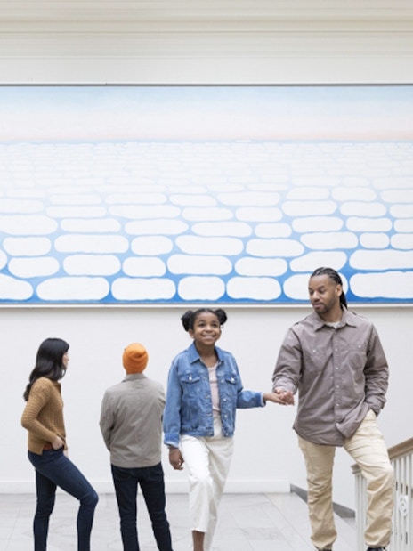 Visitors ascending stairs at The Art Institute of Chicago under a large abstract painting.
