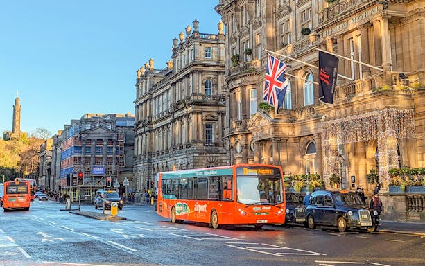 Edinburgh airport bus in front of historic Balmoral Hotel on Princes Street.