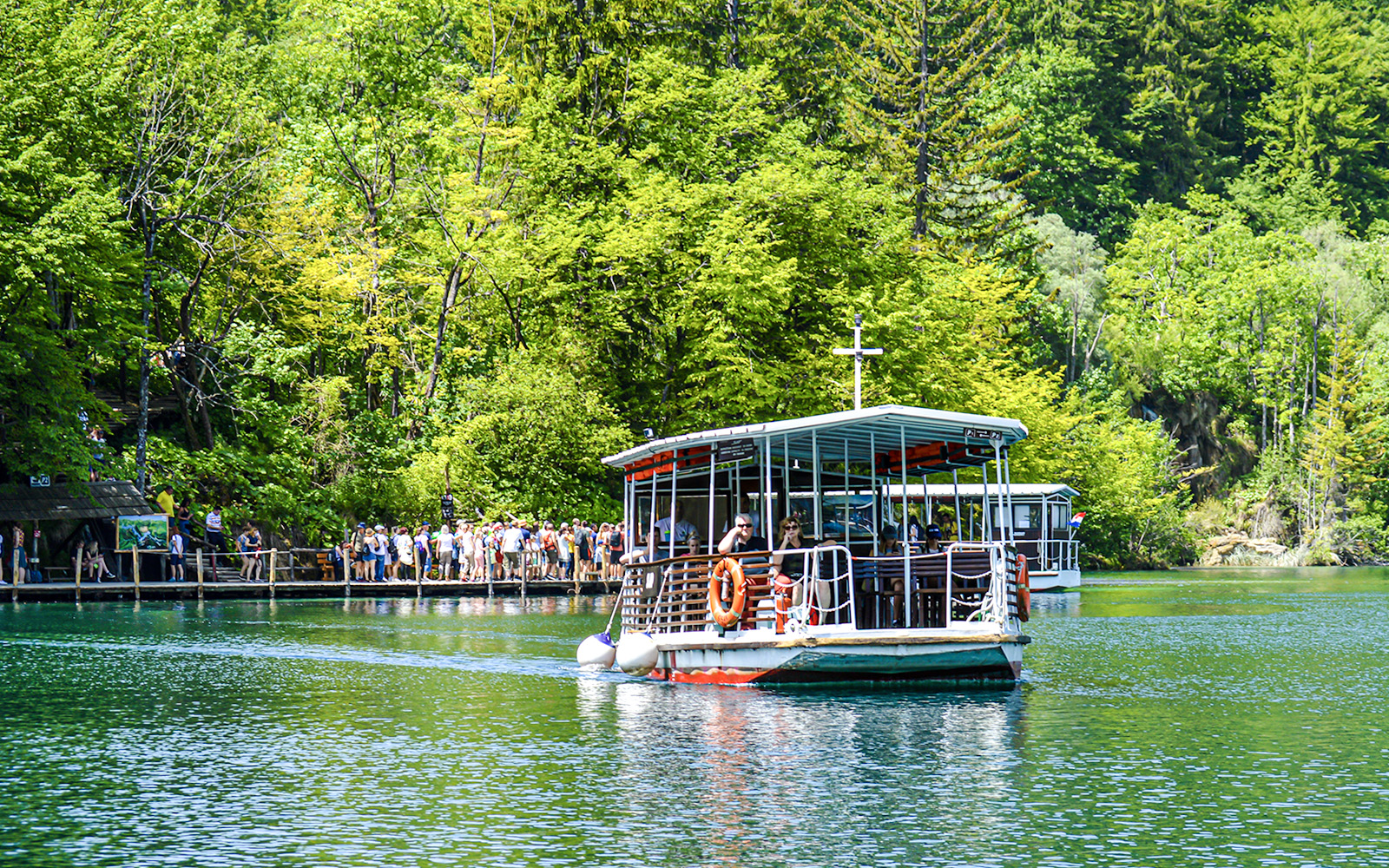 Boat tour on a lake surrounded by lush forest at Plitvice Lakes National Park, Croatia.