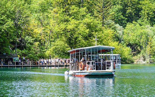 Boat tour on a lake surrounded by lush forest at Plitvice Lakes National Park, Croatia.