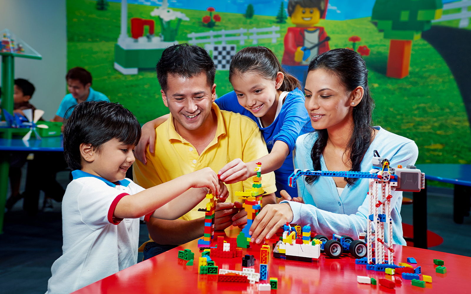 Children building with colorful bricks at Legoland Dubai interactive zone.