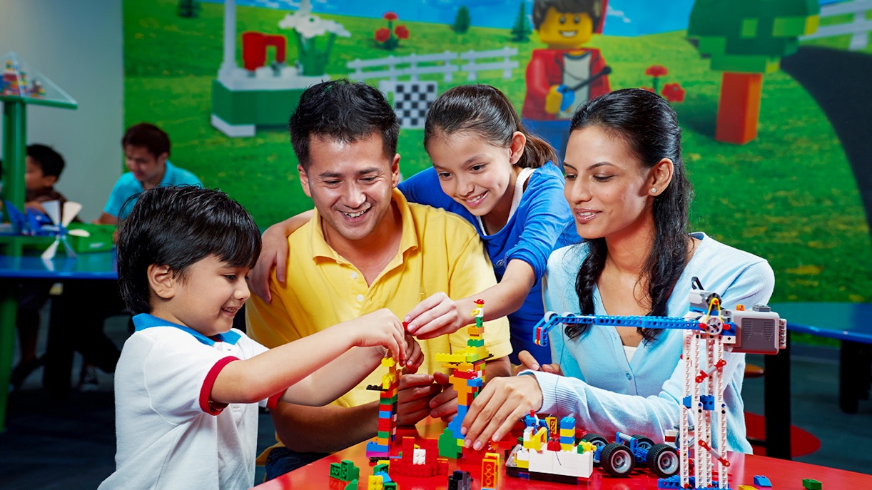 Children building with colorful bricks at Legoland Dubai interactive zone.