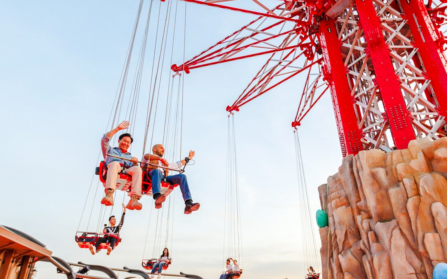 Tourists on SkyFlyers ride at Asiatique Bangkok against a clear sky.