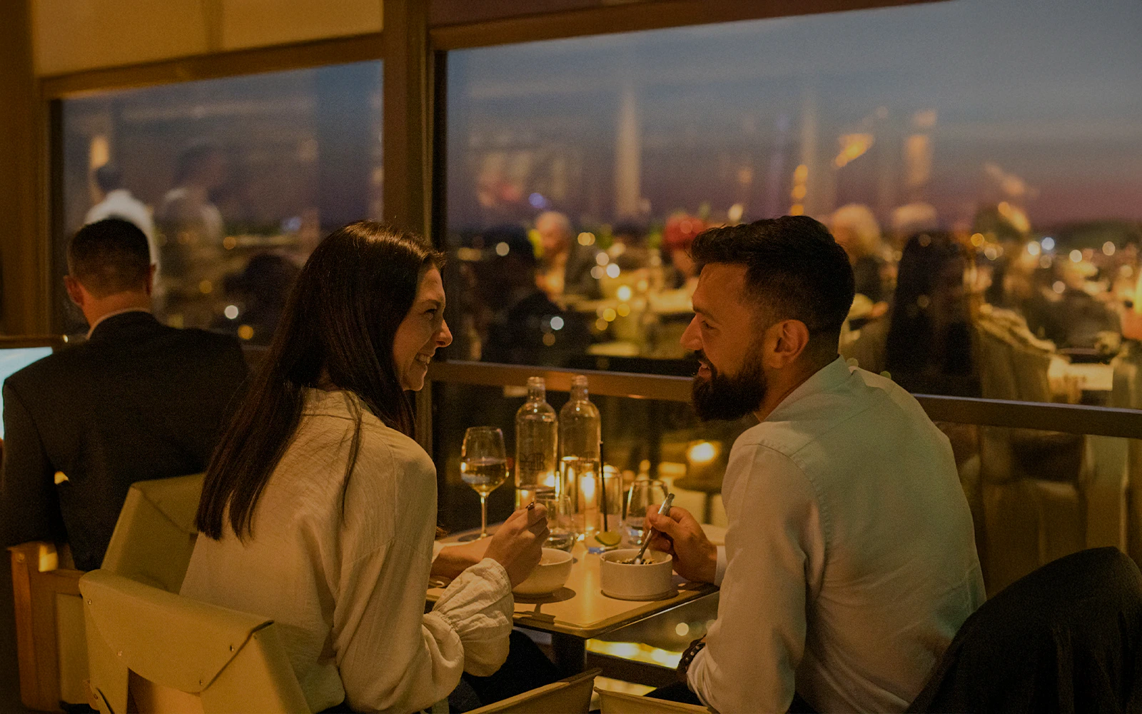 Couple dining at Madame Brasserie Eiffel Tower Restaurant with city view.