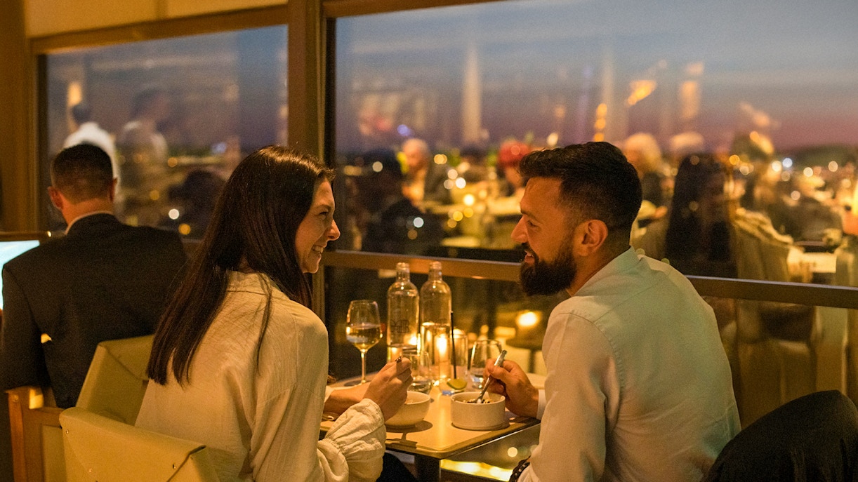 Couple dining at Madame Brasserie Eiffel Tower Restaurant with city view.