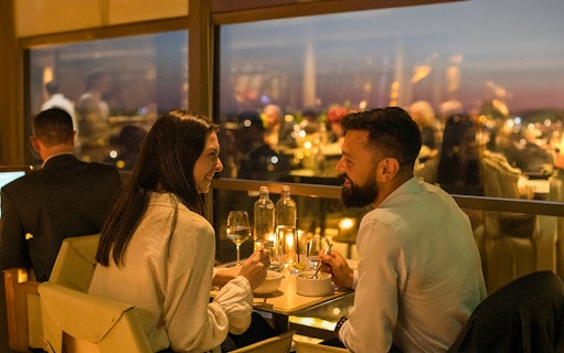 Couple dining at Madame Brasserie Eiffel Tower Restaurant with city view.