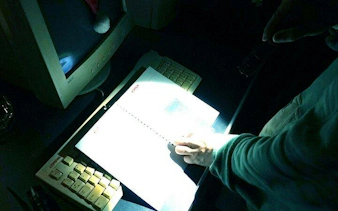 Person examining a notebook under dim light in an escape room setting, Dubai.
