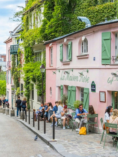 Café La Maison Rose on a cobblestone street in Montmartre, Paris, with people dining outside.