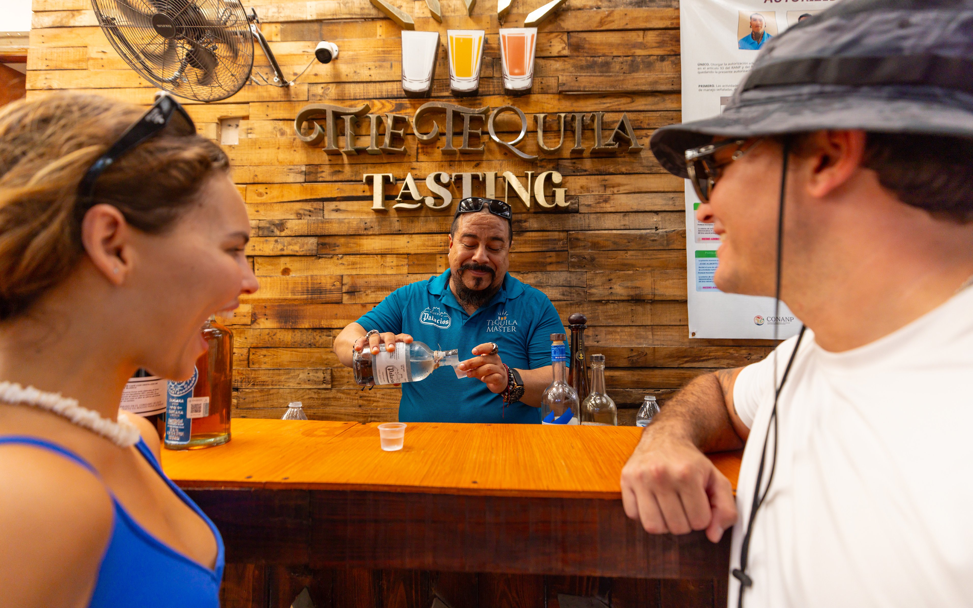 Visitors at a tequila tasting bar with a guide pouring tequila.