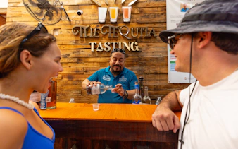 Visitors at a tequila tasting bar with a guide pouring tequila.