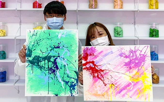Tourists displaying colorful abstract paintings in an art studio.