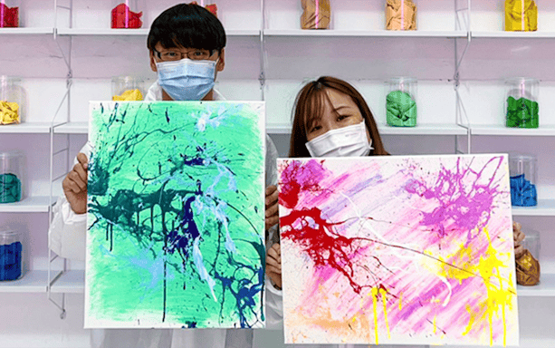 Tourists displaying colorful abstract paintings in an art studio.