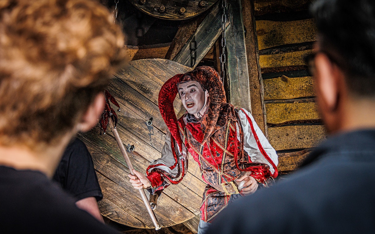 Jester performing at the Berlin Dungeon with audience in foreground.